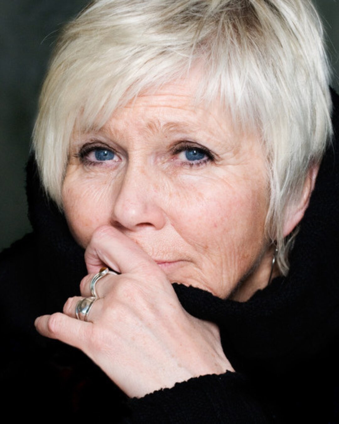 Kvinna med vit hår tittar direkt i kameran.